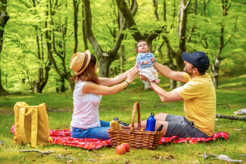 A family on a picnic day with their newborn son. Dressed in a white and yellow t-shirt