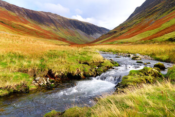 Honister Pass, a mountain pass with a narrow road winding along Gatesgarthdale Beck mountain stream. Cumbria, the Lake District, England.