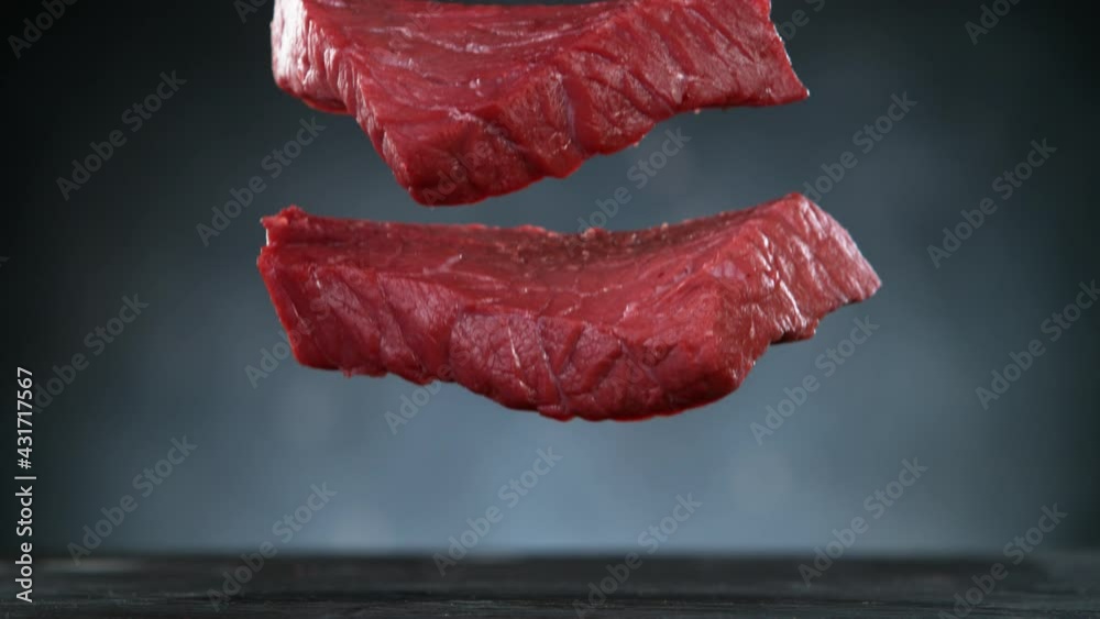 Sticker Flying pieces of raw beef steaks falling on table with spice. Filmed on high speed cinema camera, 1000 fps.