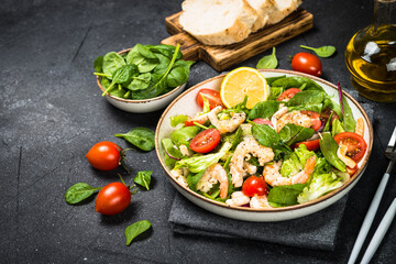 Shrimp salad with green leaves at stone table.