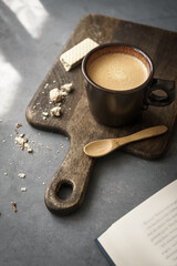 Eine braune Tasse Kaffee mit einem Holz Löffel auf einem Serviertablett und ein Keks auf einem...