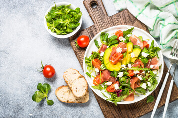 Fresh salad with green leaves, jamon and tomatoes.