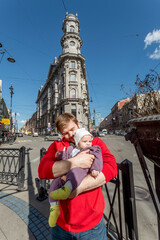 Outdoor portrait of young red-haired father holding his little toddler.