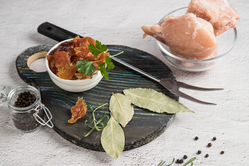 Close-up of dried chicken meat in a plate with spices and herbs on a round wooden cutting board. The concept of long-term storage of products