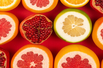 Fototapeta na wymiar Grapefruit, orange, pomegranate, citrus sweetie on red background.