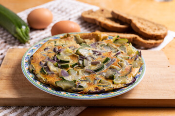 Zucchini and onion omelette served with bread. Complete vegetarian dish.