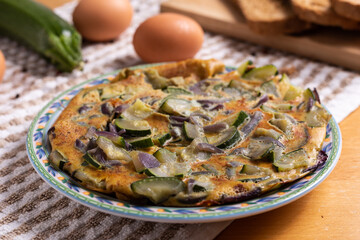 Zucchini and onion omelette served with bread. Complete vegetarian dish.