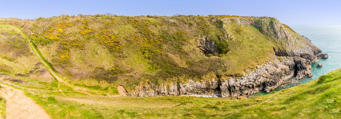A panorama view along the length of an isolated cove on the Pembrokeshire coast neart to Tenby, South Wales on a sunny day