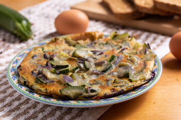 Zucchini and onion omelette served with bread. Complete vegetarian dish.