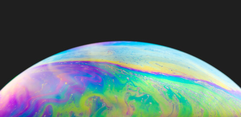 Blurred colourful soap bubble close up on black background. Creative background. Concept of space and creativity. Imitation of an unknown planet.