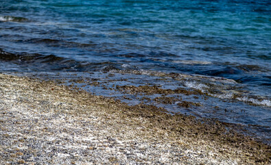 Dry crystal salt on rocky beach. Blue sea background.