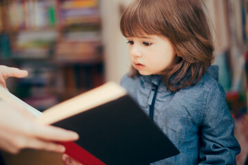 Toddler Girl Looking at a Book in a Library