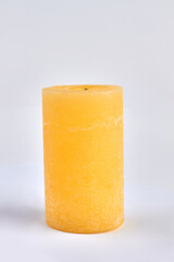 Yellow wax candle on white background. Decorative candle.