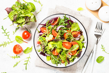 Green salad with fresh vegetables at white.