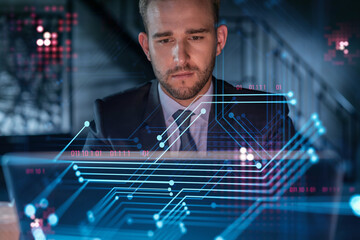 Handsome businessman in suit at workplace working with laptop to optimize development by implying...