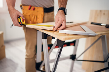 Professional carpenter at work measuring wooden planks