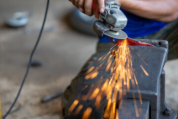Young workers use metal grinders Steel parts of a motorbike To design and modify Beautiful orange sparkle from metal grinding.