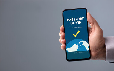 phone in hand with covid passport on screen, with gray background, gray clothes.