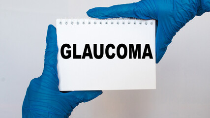 the doctor in gloves holds a card with the text GLAUCOMA . white background. the medicine