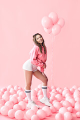 Obraz na płótnie Canvas Full length portrait of young trendy woman posing with pink balloons on pink background