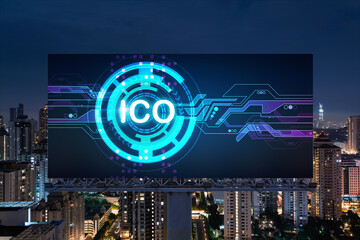 ICO hologram icon on billboard over panorama city view of Kuala Lumpur at night. KL is the hub of blockchain projects in Malaysia, Asia. The concept of initial coin offering, decentralized finance