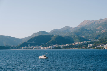 Motor boat at sea, against the backdrop of the Budva coast and mountains in Montenegro.