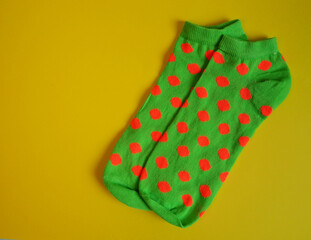 close short bright green women's socks with orange polka dots lie on a yellow background top view