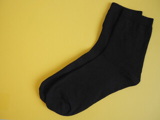 two new black socks lie on a black background top view