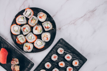 Sushi bar lunch menu - different sushi rolls with salmon, avocado and smocked eel on white marble table background with copy space - futomaki. uramaki, maki. Order food online, delivery food concept