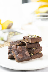 flourless pumpkin chocolate brownies set on white cafe table.