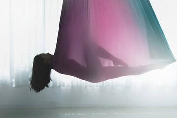 Blurred image of silhouette  Asian woman doing aerial dance practice in hammock at studio
