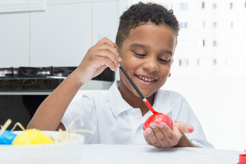 Black child having fun painting Easter egg.