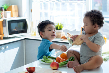 Little boy and his brother play together in kitchen at home