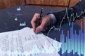 A client in formal wear is signing the contract to invest money in stock market. Internet trading and wealth management concept. Forex and financial hologram chart over the desk.