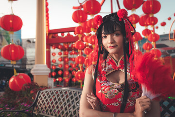 Lady in red costume in Chinese new year festival, with a lot of chinese decoration looking and smile at camera