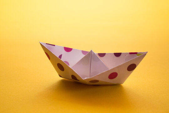origami paper boat with a yellow background