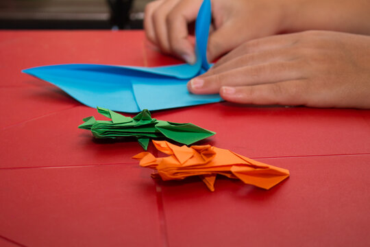 colorful origami chameleons falling on a red table