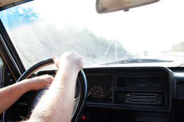 male hands on the steering wheel of an old soviet car on the way in the sun close-up