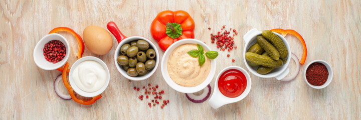 Thousand Islands sauce and ingredients - cucumbers, onions, paprika, ketchup and mayonnaise in bowls on the table. American cuisine, dip for burgers and meat. Top view