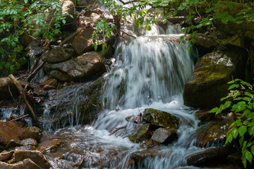 stream among the stones in the forest. water flows down the small cascades. wonderful nature background. freshness concept