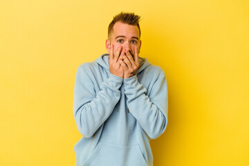 Fototapeta premium Young tattooed caucasian man isolated on yellow background shocked, covering mouth with hands, anxious to discover something new.