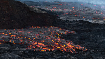 Stunning view of flowing lava with glow at eruption site of volcano in Geldingadalir valley near Fagradalsfjall mountain, Grindavík, Reykjanes peninsula, southwest Iceland in the evening.