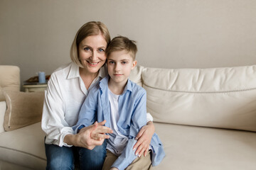 Adult woman hugs a teenager and look into the camera.