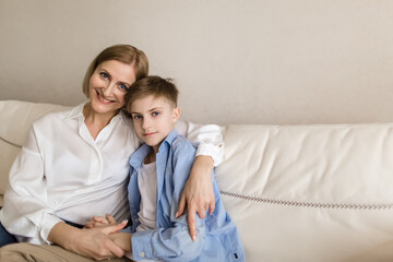 Adult woman hugs a teenager and look into the camera.