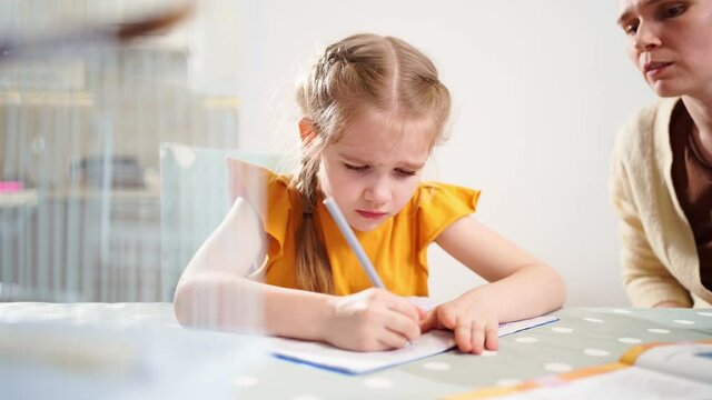 A schoolgirl does her homework and cries. mom sits next to her explains. complexities of correct and beautiful handwriting. there is no desire to learn. family and distance learning. 