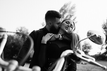 Evening walk of a biker and a girl on the river bank. Romantic evening photo session. Black and...