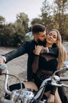Romantic vacation of a biker and a girl on the river bank. Couple in love. Evening photo session.