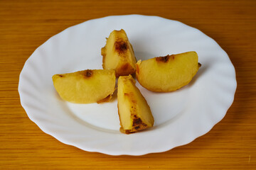 Tasty Baked Apple slices on a plate and wooden background