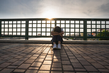 Asian woman wearing a mask, sitting on the floor of a bridge, suffering from unemployment during the coronavirus outbreak, no money.