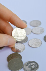 Cropped hand holding 1 Thai Baht coin in white background